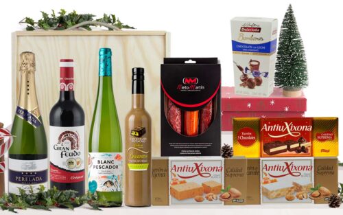 Lot gourmet amb cava Castillo Perelada Brut Reserva, vins de Navarra i Empordà, licor de xocolata i pistatxo, ibèrics, torrons i bombons praliné, presentat en una caixa de fusta amb nansa.